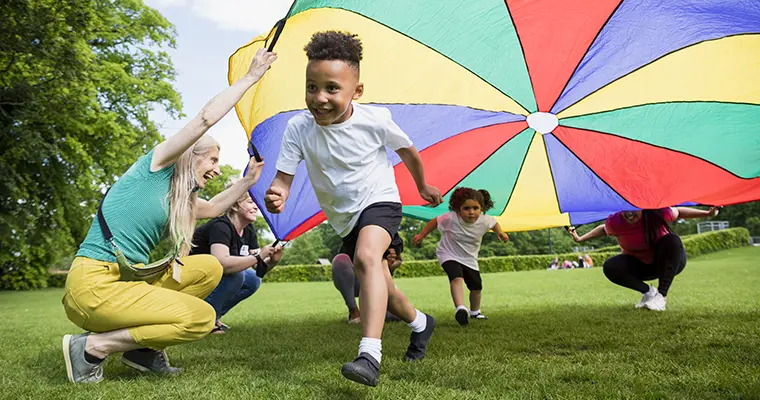 Young boy running under parachute