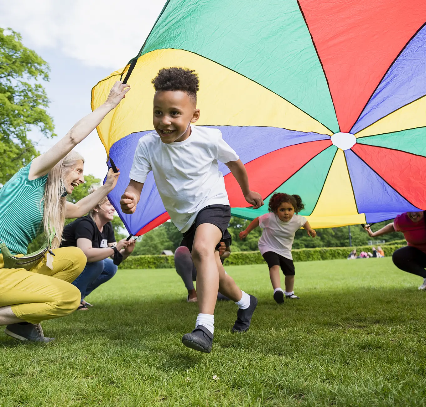 Young boy running under parachute