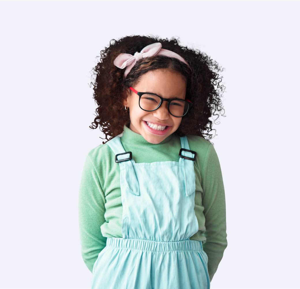Girl with dark curly hair and glasses standing with arms behind back